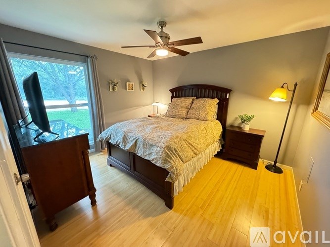 A bedroom with a bed, a television, and a ceiling fan.