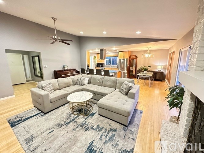 A spacious living room with a grey sofa set and a rug.