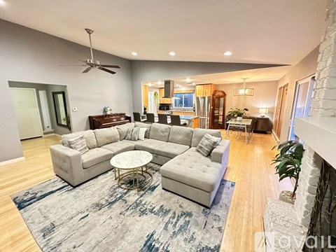 A spacious living room with a grey sofa set and a rug.
