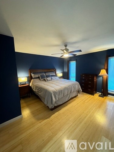 A bedroom with a bed, dresser, and ceiling fan.