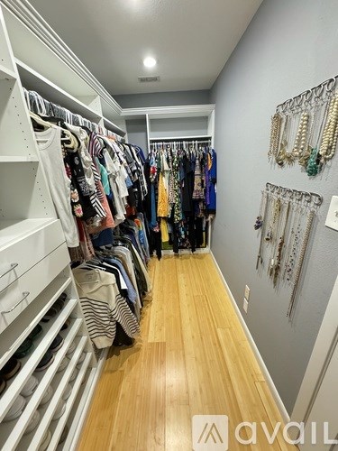 A walk in closet with clothes and jewelry.