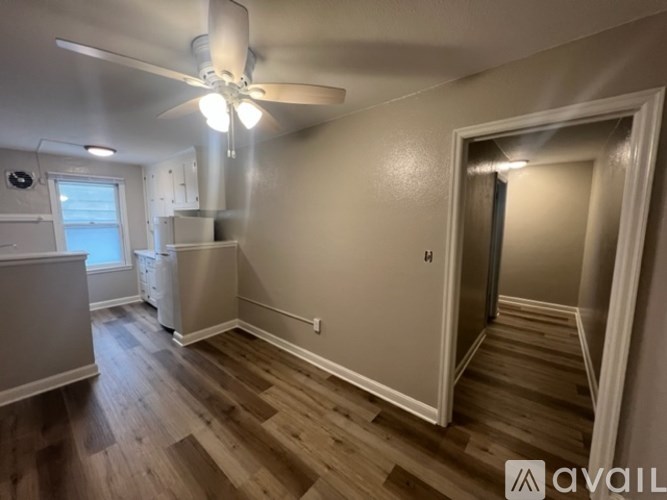 A room with a ceiling fan and wooden flooring.