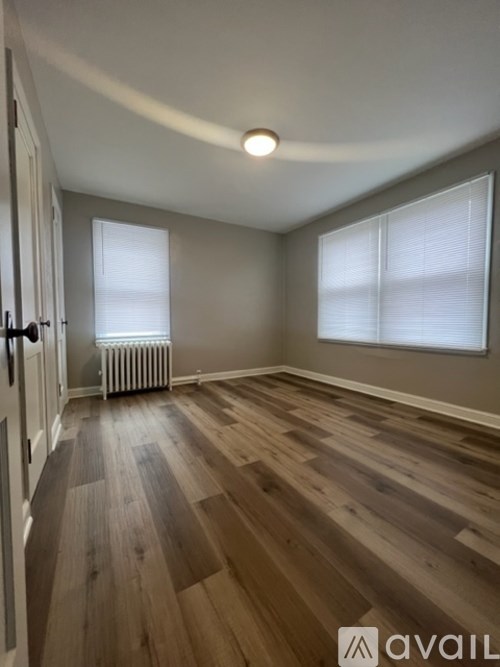 A room with wooden flooring and a window with blinds.