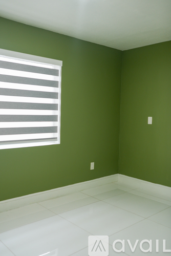 A room with green walls and a window with white blinds.