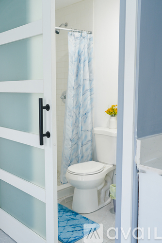 A white toilet with a blue shower curtain in the background.