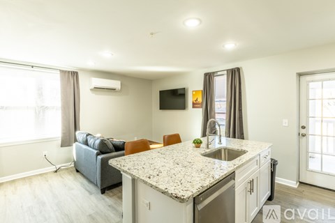 A kitchen with granite countertops and a grey sofa.