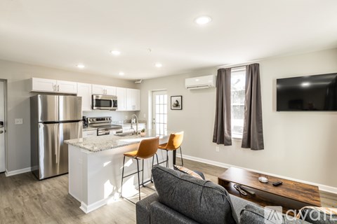 A modern kitchen with a refrigerator, microwave, and a dining table with chairs.