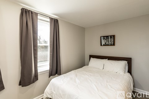A bedroom with a white bed and a picture frame on the wall.