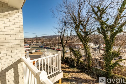 A balcony with a view of a parking lot and trees.