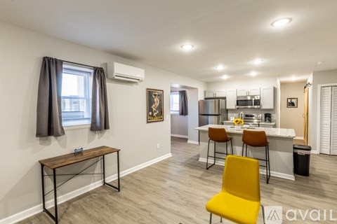 A kitchen area with a yellow chair and a table with a brown top.