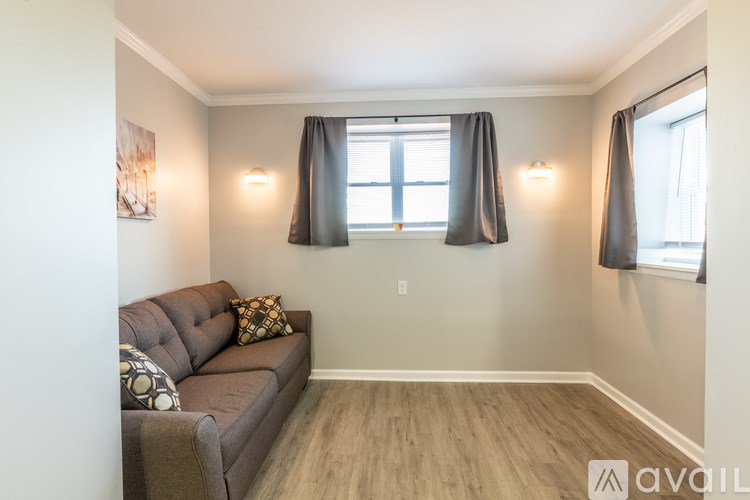 A living room with a brown couch and a window with black curtains.