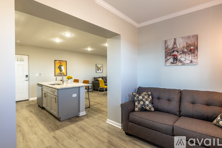 A living room with a brown couch and a kitchen area in the background.