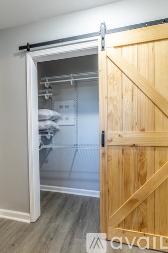 A wooden door opens to a walk-in closet with shelves and clothes.