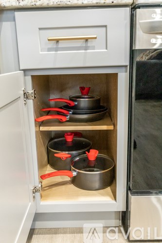 A kitchen cabinet with pots and pans inside.