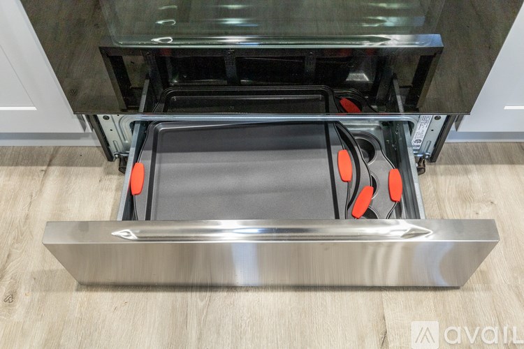 A stainless steel drawer pull with orange accents is installed in a cabinet.