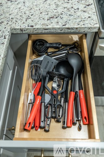 A drawer full of kitchen utensils including scissors, tongs, and spoons.