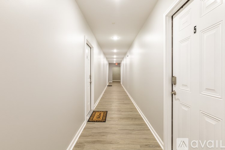 A hallway with a door on the right and a mat on the floor.