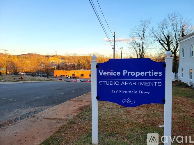 A blue sign for Venice Properties Studio Apartments stands in front of a building.