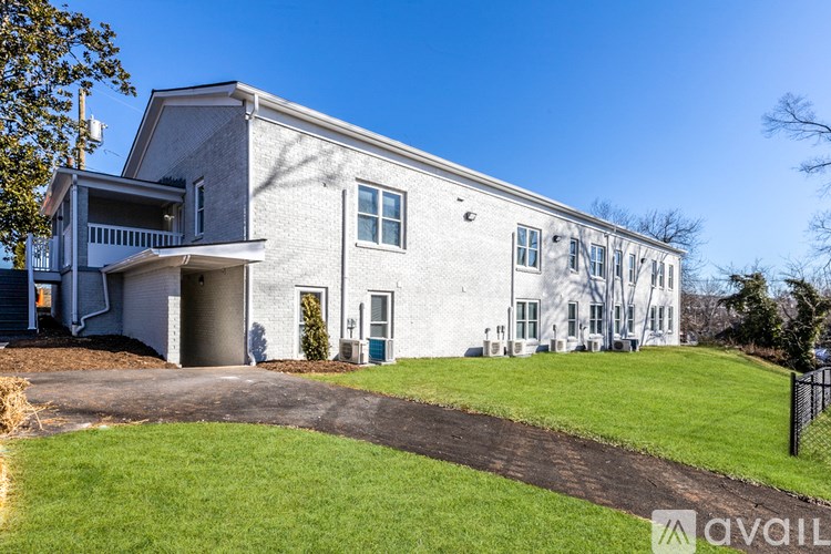 A large white building with a grey roof and a black fence in front.