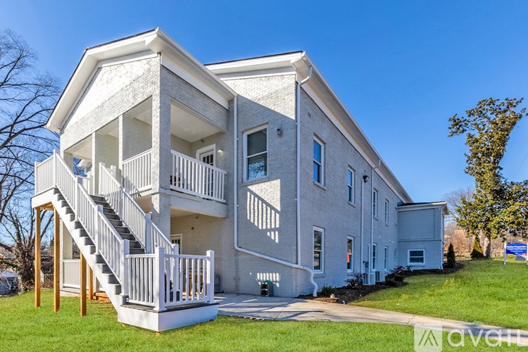 A two-story house with a white exterior and a balcony on the second floor.