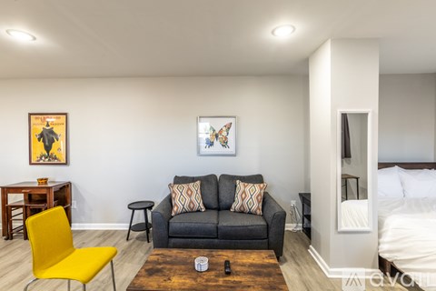A living room with a yellow chair and a black couch.