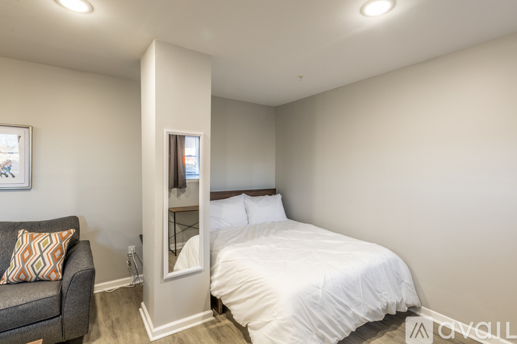 A bedroom with a bed, a couch, and a mirror.