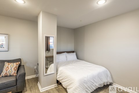 A bedroom with a bed, a couch, and a mirror.