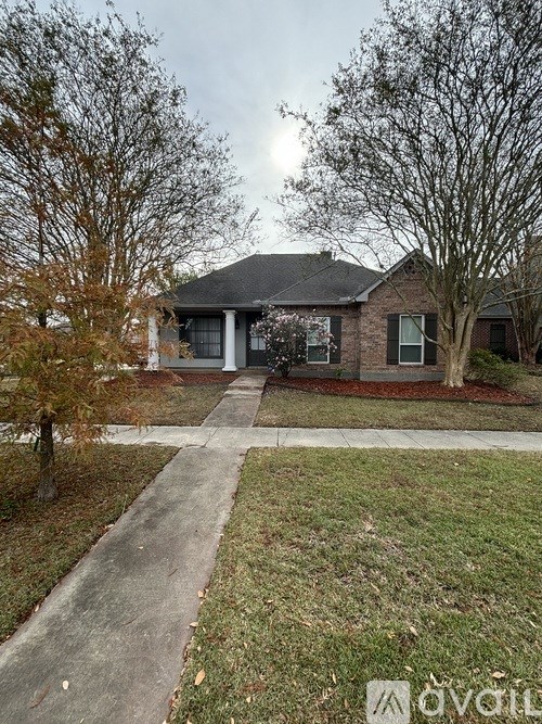 A house with a grey roof and a white fence is surrounded by trees.