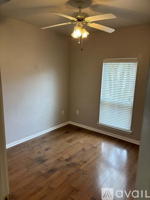 A room with a ceiling fan and a window with blinds.