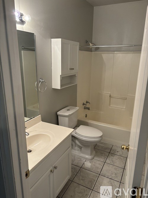A white bathroom with a toilet, sink, and mirror.