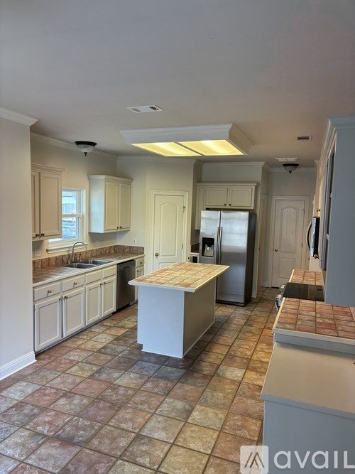 A kitchen with tile flooring and a refrigerator.