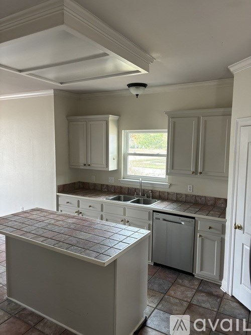 A kitchen with a tile counter top and white cabinets.