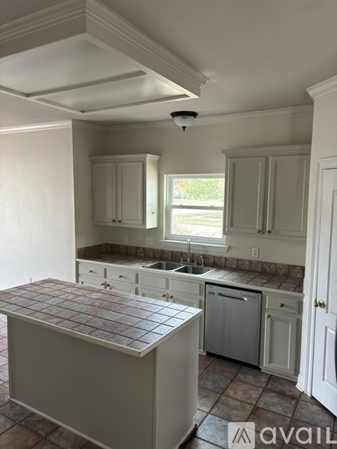 A kitchen with a tile counter top and white cabinets.