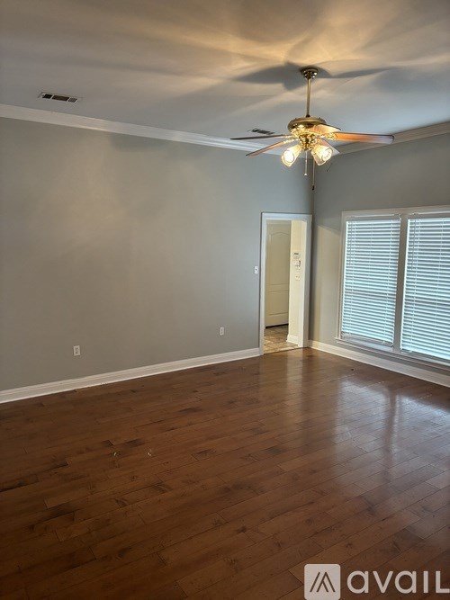 A room with a ceiling fan and wooden flooring.