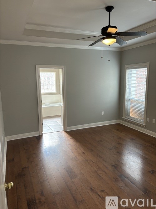 A room with a ceiling fan and wooden flooring.