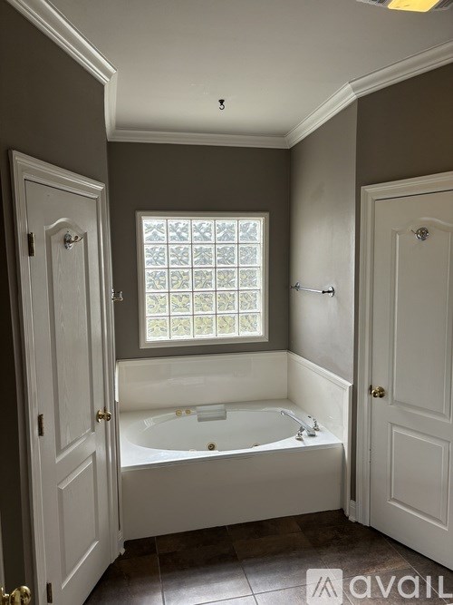 A bathroom with a bathtub, a window, and two doors.