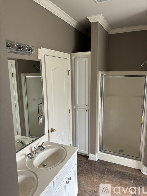 A bathroom with a white sink and a glass shower door.