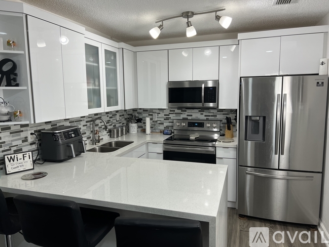 A kitchen with white cabinets and a stainless steel refrigerator.
