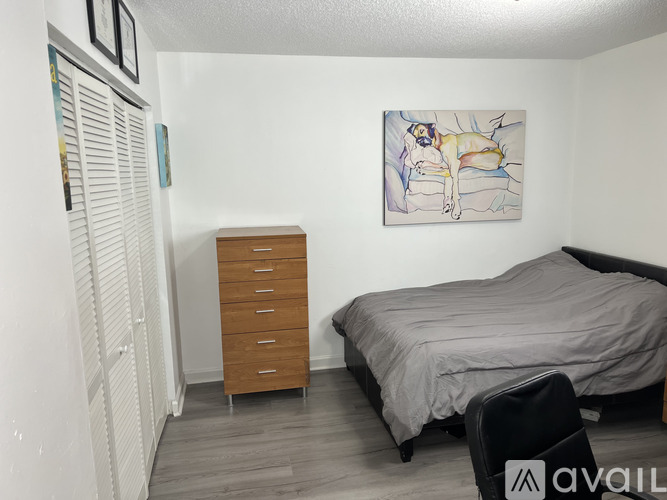 A bedroom with a bed, dresser, and a painting on the wall.