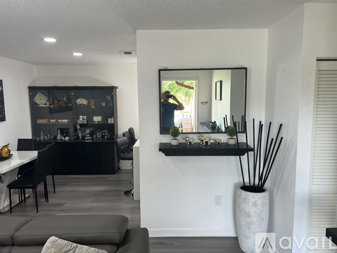 A living room with a grey couch and a large mirror on the wall.