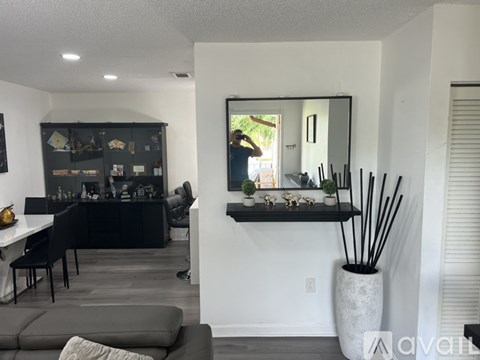 A living room with a grey couch and a large mirror on the wall.
