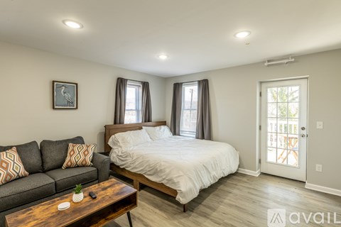 A bedroom with a bed, couch, and coffee table.