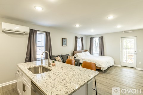 A kitchen with granite countertops and a bedroom with a bed and a window.