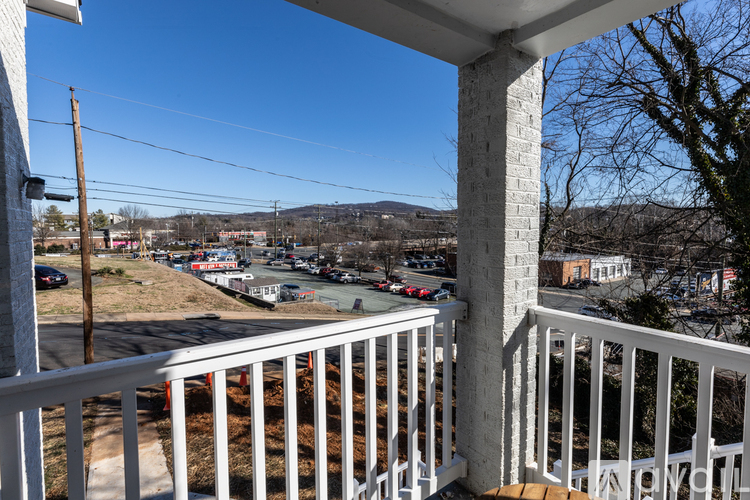 A view from a balcony overlooking a parking lot and buildings.