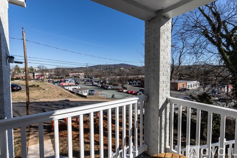 A view from a balcony overlooking a parking lot and buildings.