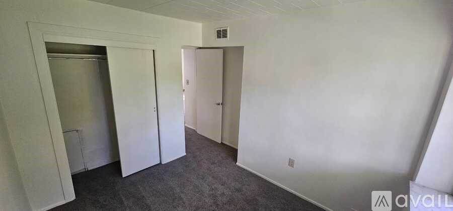 A room with a white door and a white wall with a small window.
