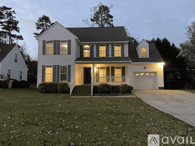 A large white house with a black roof and a garage.
