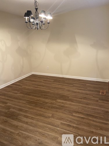 A room with wooden flooring and a chandelier.