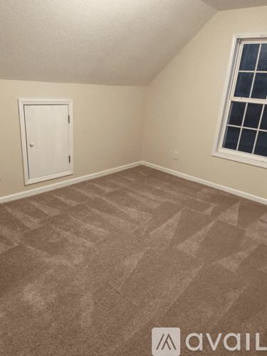 A room with a carpeted floor and a window with a white frame.