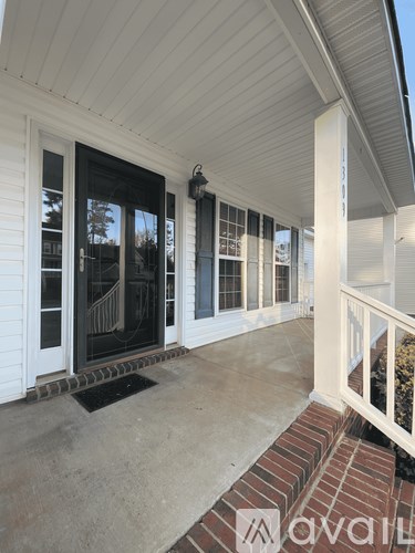 A white house with a black door and a white railing.